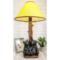 Two sibling black bear cubs sitting together with lamp statue