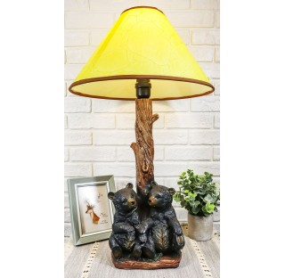 Two sibling black bear cubs sitting together with lamp statue